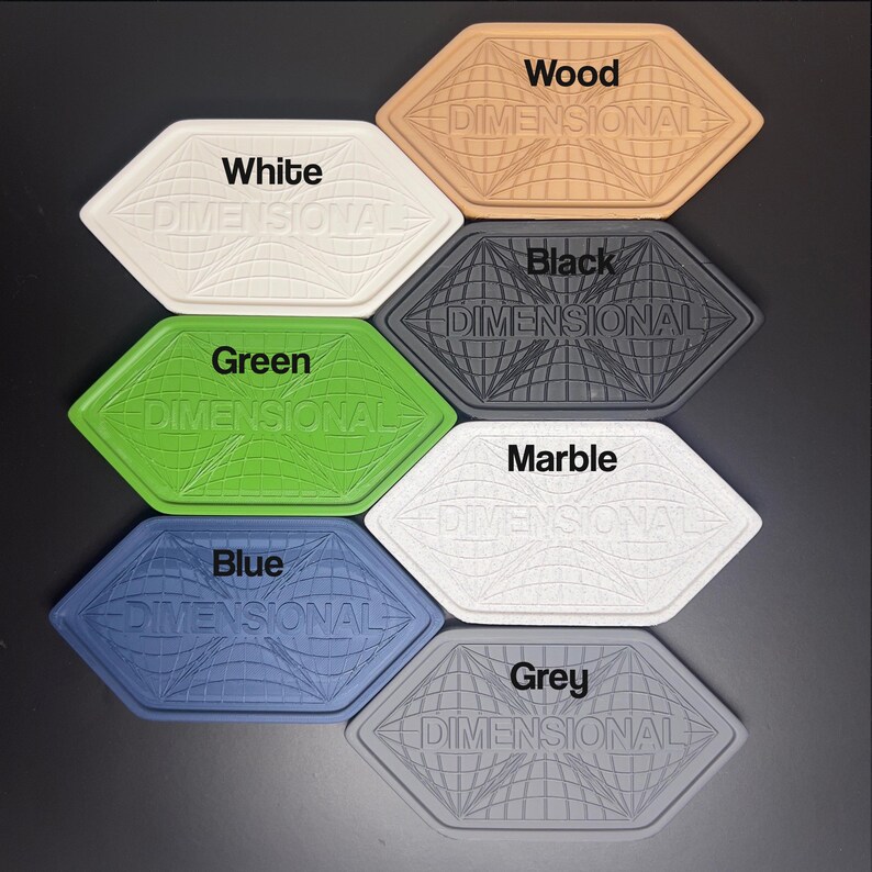 K&ouml;nnte beinhalten: Eine Sammlung von sieben sechseckigen Untersetzern in verschiedenen Farben: Wei&szlig;, Holz, Schwarz, Gr&uuml;n, Marmor, Blau und Grau. Jeder Untersetzer tr&auml;gt das Wort "DIMENSIONAL" und ein Weltkugel-Design.