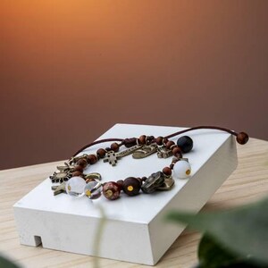 May include: A white ceramic mug with a black handle and the text "But First, Coffee" in a bold, black font. The mug is set against a blurred background, suggesting a cozy setting.