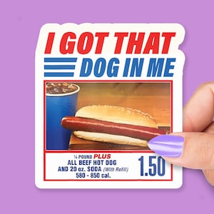May include: A sticker with the text "I GOT THAT DOG IN ME" in red and blue. The image features a hot dog, a blue soda cup, and the text "¼ POUND PLUS ALL BEEF HOT DOG AND 20 fl oz. SODA (With Refill) 580-850 cal."
