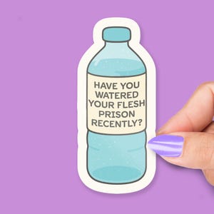 Può includere: Un adesivo a forma di bottiglia d'acqua con un design azzurro. L'adesivo presenta il testo "HAVE YOU WATERED YOUR FLESH PRISON RECENTLY?" su un'etichetta color crema. Lo sfondo è viola.