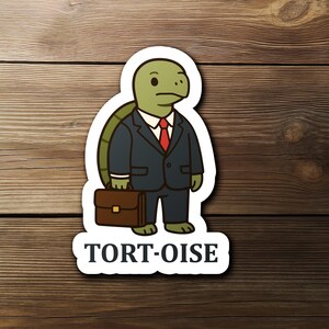 May include: A sticker featuring a cartoon tortoise in a business suit, holding a briefcase. The tortoise is green with a dark blue suit and red tie. The sticker has the word "TORT-OISE" in white letters.