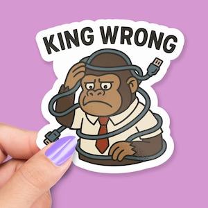 May include: A sticker with a cartoon gorilla wearing a white shirt and red tie, tangled in a USB cable. The sticker reads "KING WRONG" in black text. The gorilla has a worried expression, with a hand on its head.
