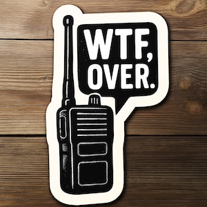May include: A black and white sticker featuring a vintage-style walkie-talkie with the text "WTF, OVER." The design is set against a cream-colored background, with a speech bubble shape. The sticker is placed on a wooden surface.