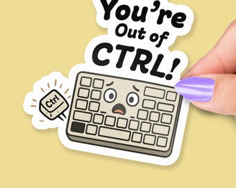 以下が含まれることがあります： 「You're Out of CTRL!」の文字と、困った表情の漫画のキーボードが描かれたステッカー。別の「Ctrl」キーも表示されています。紫色のマニキュアを塗った手でステッカーを持っています。