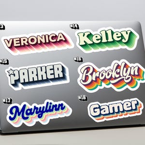 May include: A selection of retro-style name and word stickers displayed on a laptop. The stickers include names such as "Veronica," "Kelley," "Parker," "Brooklyn," "Marylinn," and the word "Gamer," each with distinct colours and 3D effects.