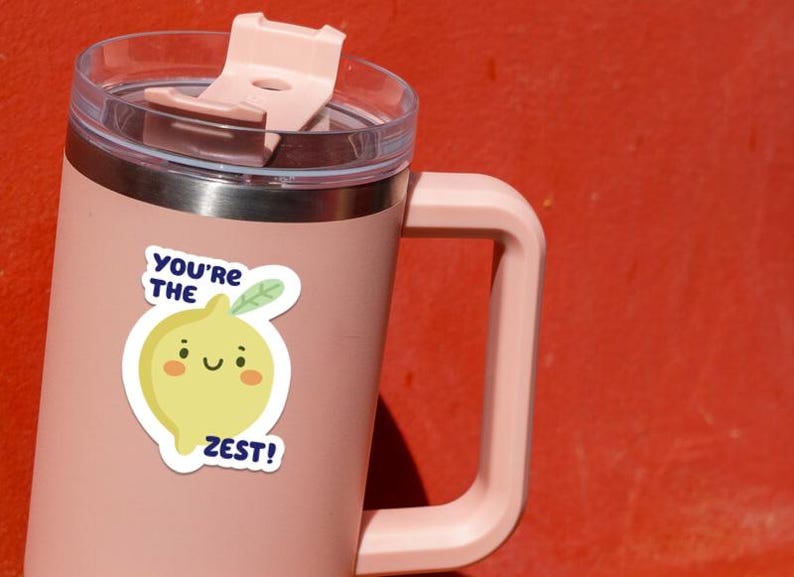 May include: A pink stainless steel travel mug with a lid and a lemon sticker that says "You're the Zest!"