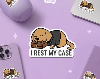 May include: A collection of stickers featuring a cartoon dog sleeping on a briefcase, wearing a suit. The text "I REST MY CASE" is below the dog. The stickers are on a purple background with a phone, laptop, and water bottle.