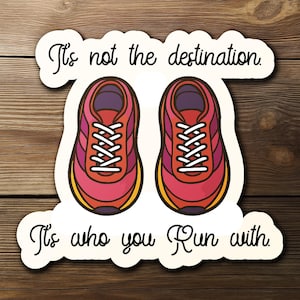 May include: A sticker featuring two running shoes in shades of red, pink, and purple with white laces. The text reads "It's not the destination. It's who you run with."
