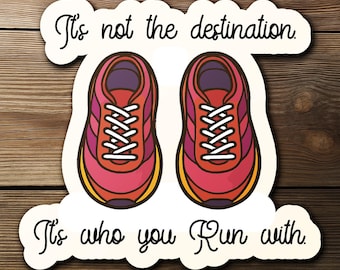 May include: A sticker featuring two running shoes in shades of red, pink, and purple with white laces. The text reads "It's not the destination. It's who you run with."