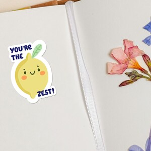 May include: A yellow lemon sticker with a smiling face and green leaves. The sticker says "You're the Zest!" in blue text.