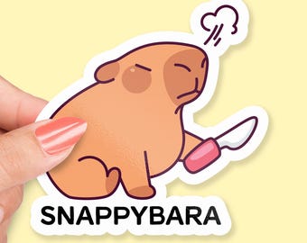 Peut inclure: Un autocollant représentant un capybara de dessin animé tenant un couteau avec une poignée rose. Le capybara a une expression grincheuse et souffle une bouffée d'air. Le texte "SNAPPYBARA" est imprimé sous le capybara.