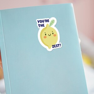 May include: A blue notebook with a yellow lemon sticker that says "You're the Zest!"