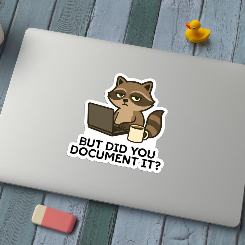 Puede incluir: Una pegatina con un mapache de dibujos animados trabajando en un port&aacute;til con una taza de caf&eacute;. El mapache tiene una expresi&oacute;n de mal humor. El texto de la pegatina dice: "&iquest;PERO LO DOCUMENTASTE?"