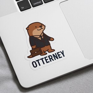 K&ouml;nnte beinhalten: Ein Aufkleber mit einem Cartoon-Otter in einem Anzug, der eine Aktentasche h&auml;lt. Der Otter ist braun und hellbraun und tr&auml;gt einen schwarzen Anzug und eine Krawatte. Das Wort "OTTERNEY" ist darunter in Marineblau gedruckt.