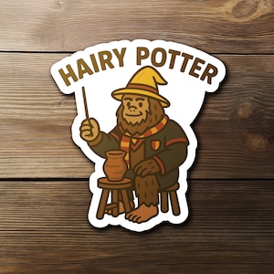 May include: A sticker featuring a cartoon Bigfoot character dressed as a wizard, holding a wand and sitting on a stool. The sticker has the words "HAIRY POTTER" in a brown, stylized font across the top.