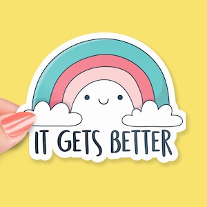 Puede incluir: Una pegatina con un arcoíris, nubes y el texto "IT GETS BETTER". El arcoíris es rosa, azul y blanco. Las nubes son blancas. El texto es negro.