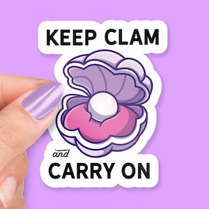 Puede incluir: Pegatina blanca con una concha de almeja morada con una perla en su interior. El texto de la pegatina dice "Keep Clam and Carry On."