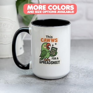 Puede incluir: Taza de cerámica blanca con asa e interior negros. La taza presenta un loro de dibujos animados sosteniendo una calculadora con el texto "This CAWWS for a Spreadsheet". Una pancarta en la parte superior dice "MORE COLORS AND SIZE OPTIONS AVAILABLE!"