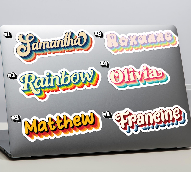 May include: A selection of name stickers in a retro style, featuring names such as "Samantha", "Roxanne", "Rainbow", "Olivia", "Matthew", and "Francine". Each sticker has a colourful, layered design with a white border for personalisation.