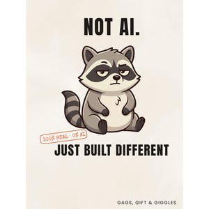 May include: A graphic print featuring a cartoon raccoon with a skeptical expression. The text reads NOT AI. JUST BUILT DIFFERENT. A small red stamp says 100% REAL 0% AI. The bottom right corner includes the text GAGS, GIFT & GIGGLES on a light background.