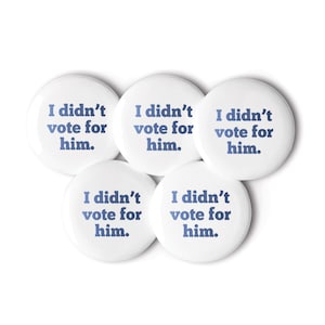 May include: Five white round buttons with blue text that reads "I didn't vote for him."