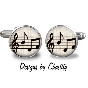 May include: Silver cufflinks with a musical note design. Each cufflink features a black treble clef and musical notes on a cream-colored background. The text "Designs by Chastity" is printed below the cufflinks.