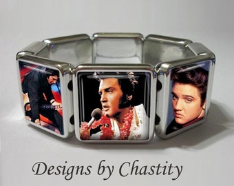 May include: Silver-toned stretch bracelet featuring square panels with images of Elvis Presley. The bracelet showcases multiple images of Elvis in different poses. The text "Designs by Chastity" is printed in a cursive font.