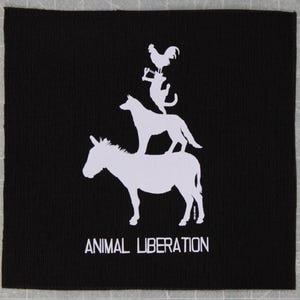 May include: Black square patch with a white graphic of a donkey, dog, cat, and rooster stacked on top of each other. The words "ANIMAL LIBERATION" are printed in white at the bottom of the patch.