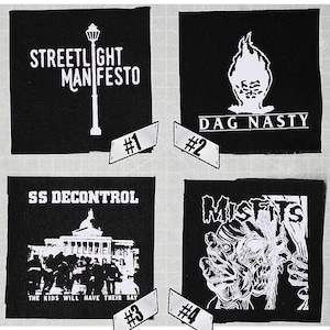 May include: Four black and white iron-on patches with band logos. The patches are numbered 1 through 4. Patch 1 features the text "STREETLIGHT MANIFESTO" with a streetlight graphic. Patch 2 features the text "DAG NASTY" with a flame graphic. Patch 3 features the text "SS DECONTROL" with a building graphic and the text "THE KIDS WILL HAVE THEIR SAY". Patch 4 features the text "MISFITS" with a skull graphic.