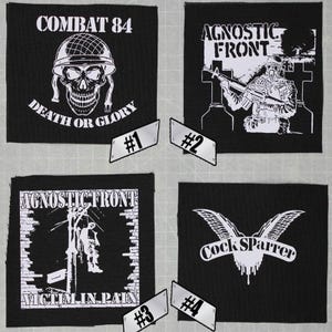 May include: Four black and white iron-on patches. The first patch features a skull with the text "Combat 84" and "Death or Glory". The second patch features a figure holding a rifle with the text "Agnostic Front". The third patch features a figure hanging from a pole with the text "Agnostic Front" and "Victim in Pain". The fourth patch features a bird with the text "Cock Sparrer".