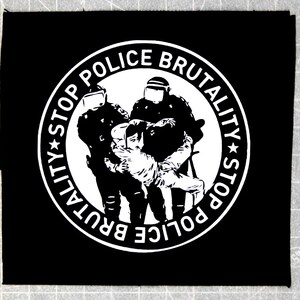 May include: Black and white patch with a circle design. The circle has the text "STOP POLICE BRUTALITY STOP" written around the outside. Inside the circle, there is a graphic of two police officers holding a person.