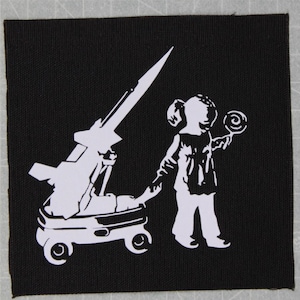 May include: A black and white patch with a silhouette of a child holding a lollipop and pulling a toy rocket on wheels.