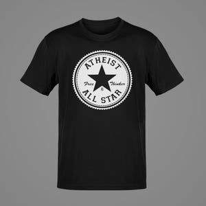 May include: Black t-shirt featuring a white circular design with the words "ATHEIST ALL STAR" and a star in the center. The text "Free Thinker" is also included in the design. The shirt has short sleeves and a crew neck.