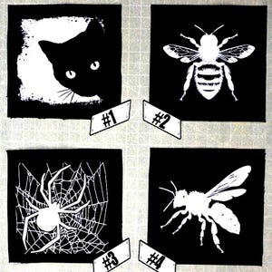 May include: Four black and white iron-on patches. The first patch features a black cat peeking out from the left side of the frame. The second patch features a white bee with black stripes. The third patch features a white spider in a web. The fourth patch features a white bee with black stripes.