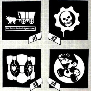 May include: Four black squares with white graphic designs. The designs include a pixelated ox pulling a wagon with text, a skull inside a gear, a geometric shape with hearts, and a cartoon of Mario.