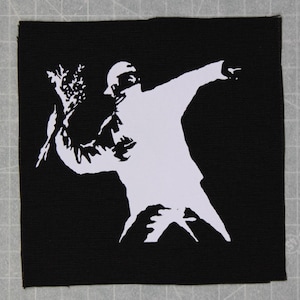 May include: A white silhouette of a person throwing a bouquet of flowers, against a black background. The person is wearing a hat and has their arm outstretched.