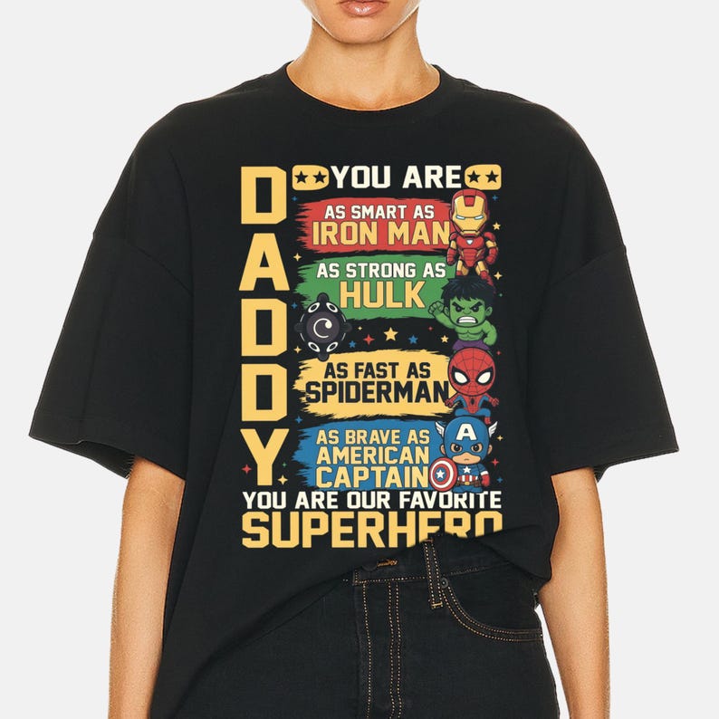 May include: Black t-shirt with the text "DADDY YOU ARE" and superhero references. The shirt features illustrations of Iron Man, Hulk, Spiderman, and Captain America, with text describing each superhero's qualities. The phrase "YOU ARE OUR FAVORITE SUPERHERO" is also included.