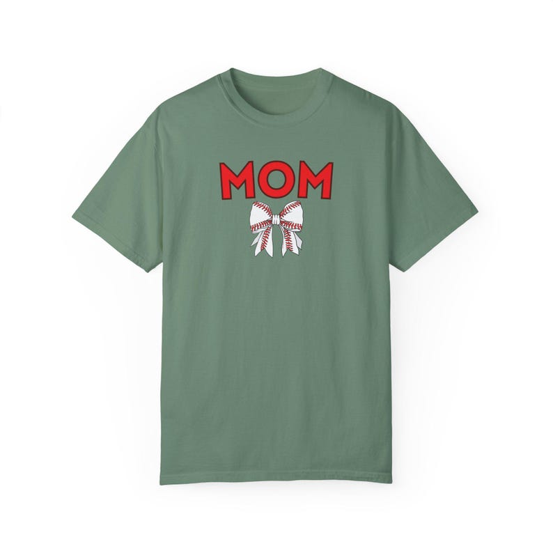 Peut inclure: Un t-shirt vert avec le mot "MOM" en lettres rouges et un n&oelig;ud blanc avec des coutures rouges.