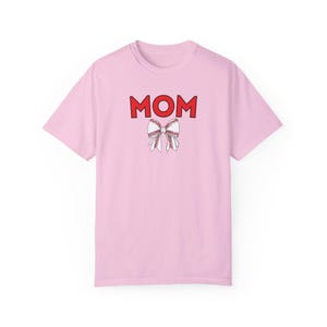 Peut inclure: T-shirt rose avec le mot "MOM" en lettres rouges et un n&oelig;ud blanc sur le th&egrave;me du baseball.