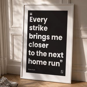 May include: A rectangular framed wall art piece featuring a black background with white text that reads, "Every strike brings me closer to the next home run" followed by the name "Babe Ruth" and a small logo in the bottom right corner.