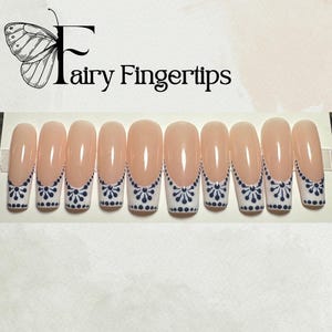 May include: Set of ten nude-colored fake nails with a white tip and a black and white polka dot design.