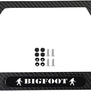May include: Black carbon fiber license plate frame with the text "BIGFOOT" and a white silhouette of a Bigfoot on each side. The frame comes with screws and caps.