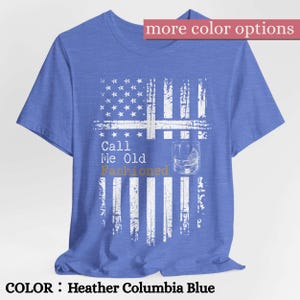 May include: A heather Columbia blue short-sleeve t-shirt featuring a white distressed American flag graphic. The design includes the text "Call Me Old Fashioned" in white and gold, accompanied by a line drawing of a glass with a citrus wedge.