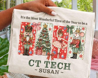 Puede incluir: Una camiseta color crema con un gráfico navideño que muestra un cascanueces, un árbol decorado, una bailarina y un ratón con uniforme. El texto dice, It's the Most Wonderful Time of the Year to be a CT TECH SUSAN.