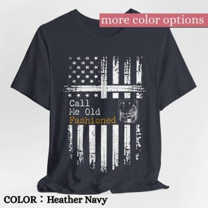 May include: A heather navy short-sleeve t-shirt featuring a distressed white graphic of the American flag. The design includes a glass of whiskey and the text Call Me Old Fashioned in white and gold lettering centered on the front chest.