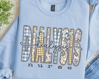 Puede incluir: Una sudadera de cuello redondo azul claro con el texto DIALYSIS en grandes letras de bloque estampadas con diseños de cuadros vichy, flores y tartán, acentuadas por dos lazos azul claro. La palabra nurse está impresa debajo en marrón.