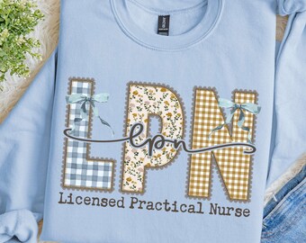 Puede incluir: Una sudadera de cuello redondo azul claro con las letras LPN en una fuente grande y decorativa. La L es de cuadros azules, la P es floral y la N es de cuadros color canela. Cada letra tiene un lazo y el texto Licensed Practical Nurse.