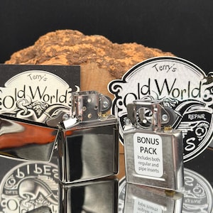 May include: Two silver-colored metal lighter inserts, one with an open lid and one with a white sticker reading BONUS PACK Includes both regular and pipe inserts, positioned in front of two circular black and white Terry's Old World logos.