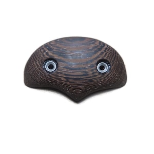 May include: A wooden, decorative object with a dark brown, textured surface. The object has a rounded top with two circular, silver-rimmed holes. The bottom of the object tapers to a point. The object is set against a white background.