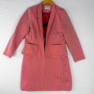 May include: A two-piece set consisting of a blazer and a skirt, both featuring a red and white vertical striped pattern. The blazer has long sleeves, two front patch pockets, and a label inside reading Henry Lee. The skirt is knee-length.